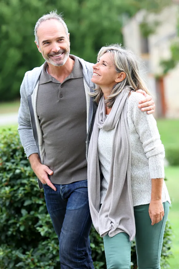 Bioidentical-Hormone-Therapy-Treatment A mature couple in gray toned clothes and jeans walk happily outside, happy with their successful bioidentical hormone treatments from Healthy Aging Medical Centers of New Jersey in Northern New Jersey.