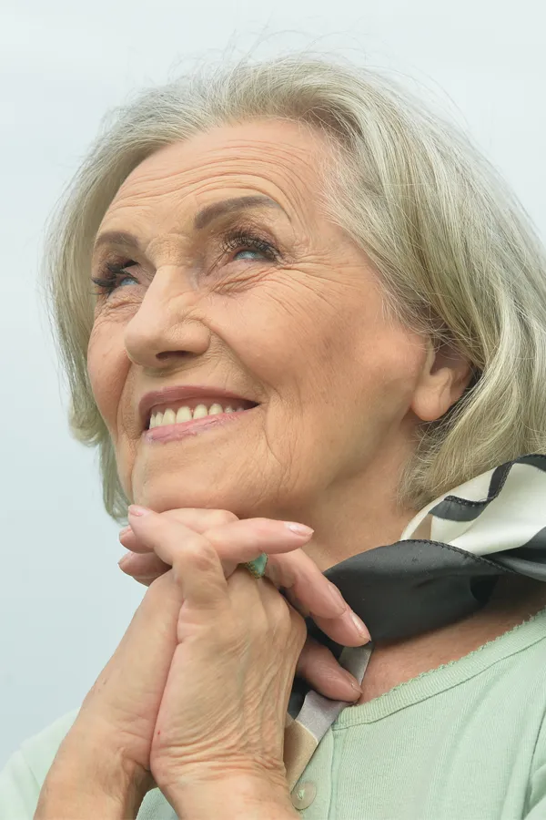 Hot-Flashes-and-Night-Sweats-Treatments An older woman holds her hands together under her chin and looks up at a cool sky smiling. Get treatment for hot flashes and night sweats from Healthy Aging Medical Centers of New Jersey in Northern New Jersey.