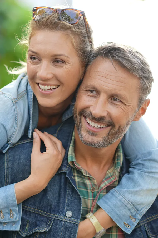 Hypogonadism-Treatment A couple in denim jackets embrace playfully outdoors. Get hypogonadism treatment from Healthy Aging Medical Centers of New Jersey in Northern New Jersey.