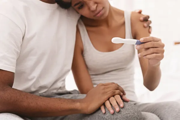 Infertility-Clinic A black couple sits on a bed, disappointed with the negative results of a pregnancy test. Get treatment for infertility from Healthy Aging Medical Centers of New Jersey in Northern New Jersey.