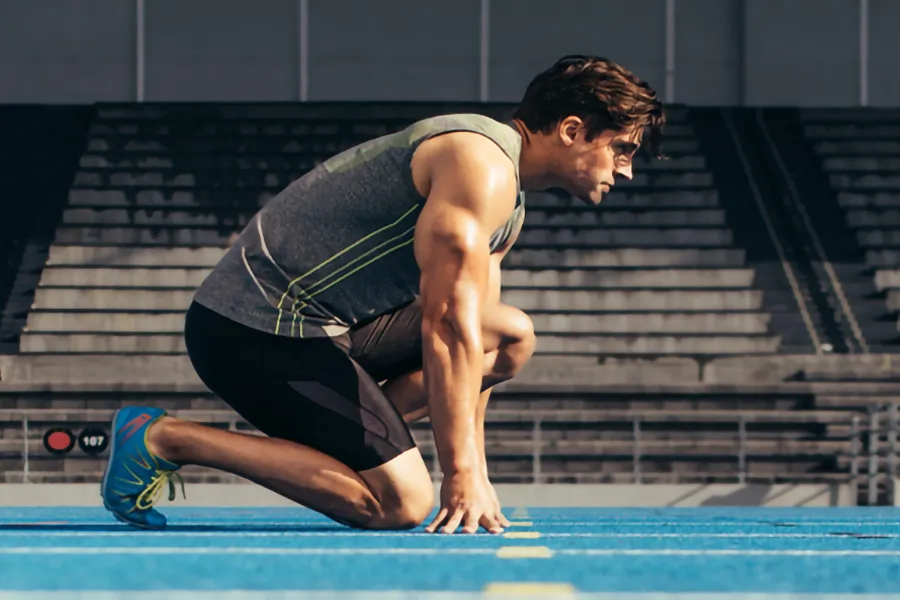 Lean-Muscle-and-Recovery-Clinic A white man kneels at the starting line on a track, determined to do his best. Get treatment for lean muscle loss and recovery from Healthy Aging Medical Centers of New Jersey in Northern New Jersey.