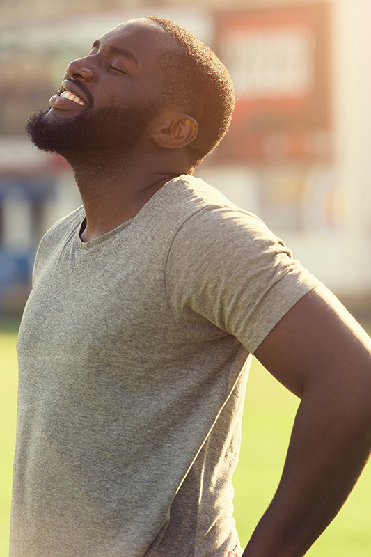 Lean-Muscle-and-Recovery-Treatment A black man in a gray t-shirt and smiles, looking up with closed eyes after a satisfying workout. Get treatment for lean muscle loss and recovery from Healthy Aging Medical Centers of New Jersey in Northern New Jersey.