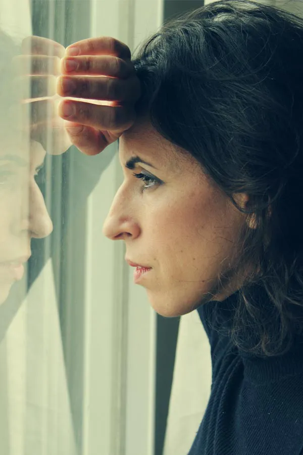 PCOS-Treatment A brunette woman in a thin dark turtleneck looks out the window with a serious expression, suffering from PCOS. Get treatment for Polycistic Ovarian Syndrome/PCOS from Healthy Aging Medical Centers of New Jersey in Northern New Jersey.
