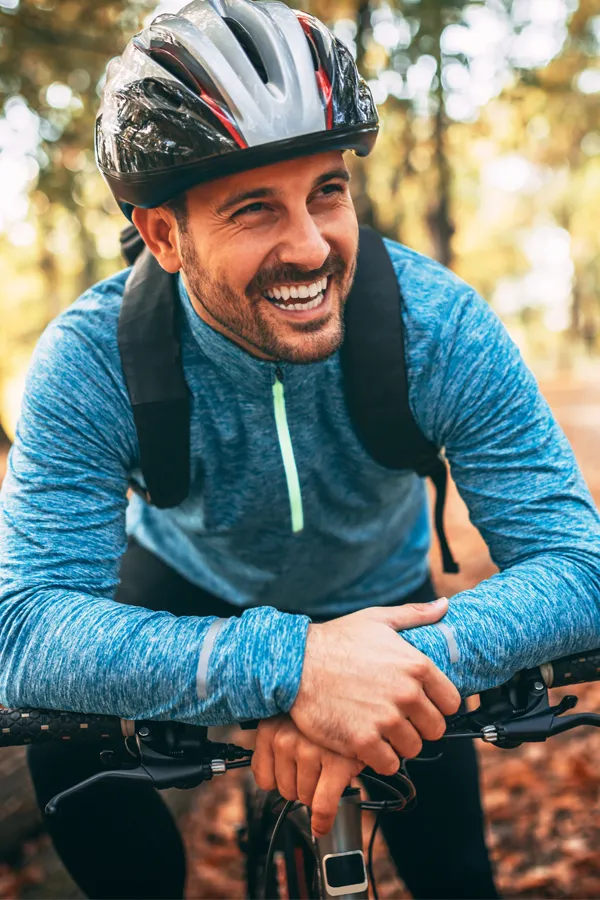 Testosterone-Low-T-Solutions-Treatment A middle-aged man on a trail in cycling clothes is smiling and leaning on his bike's handlebars. Get testosterone for Low T from Healthy Aging Medical Centers of New Jersey in Northern New Jersey.
